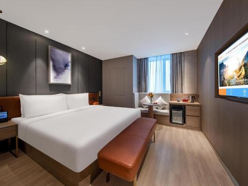 um quarto de hotel com uma cama grande e uma televisão de ecrã plano em Ji Hotel Shanghai Hongqiao Gubei Fortune Center em Xangai