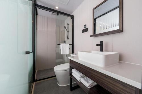 uma casa de banho com um lavatório, um WC e um espelho. em Ji Hotel Shanghai Hongqiao Gubei Fortune Center em Xangai