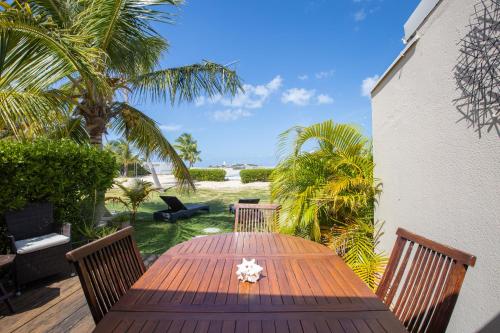 un tavolo in legno con sedie e palme su un patio di Aloe Casa - Saint-Martin Baie Nettlé - appartement sur mer a Baie Nettle