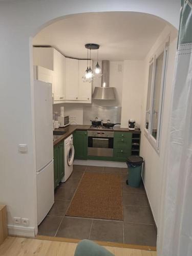 une cuisine avec des armoires vertes et un réfrigérateur blanc dans l'établissement Jolie 4 pièces, gare de train à 150 m pour aller sur Paris en 15 min, à Deuil-la-Barre