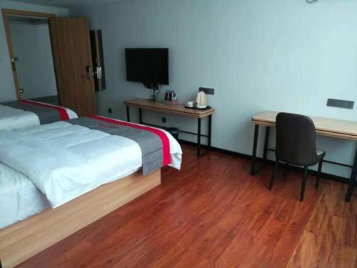una camera d'albergo con 2 letti, una scrivania e una TV di Jun Hotel Guangdong Zhanjiang Xiashan South Railway Station a Zhanjiang