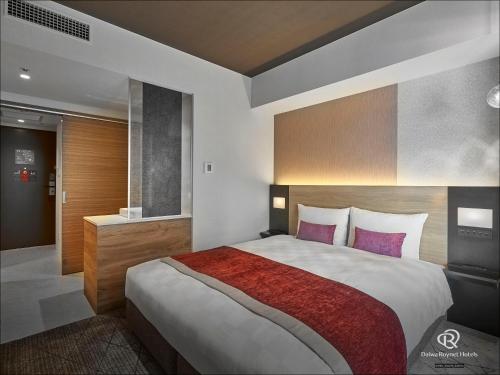 a bedroom with a large bed with purple pillows at Daiwa Roynet Hotel Osaka Sakaisuji Honmachi PREMIER in Osaka