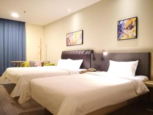 two beds in a hotel room with white sheets at Hanting Hotel Datong Xihuan Road in Datong