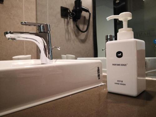 a bathroom sink with a soap dispenser next to it at Hanting Hotel Datong Xihuan Road in Datong