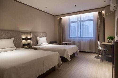 a hotel room with two beds and a window at Hanting Hotel Heze Zhonghua Road Ginza in Heze