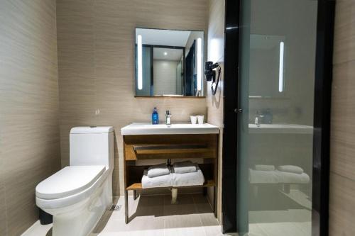 a bathroom with a toilet and a sink and a mirror at Hanting Hotel Heze Zhonghua Road Ginza in Heze
