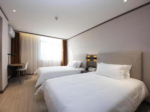 Hanting Hotel Hefei Baoye Dongcheng Plaza في خفي: سريرين في غرفة الفندق ذات شراشف بيضاء