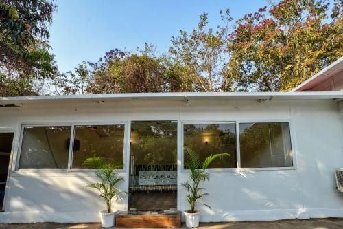 a white house with windows and two palm trees at Amore Serenity Resort in Arambol
