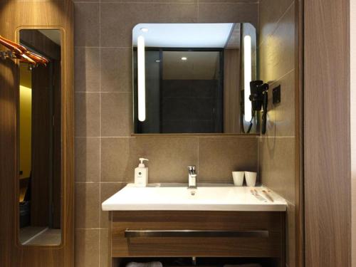 a bathroom with a white sink and a mirror at Hanting Hotel Hefei Baoye Dongcheng Plaza in Hefei