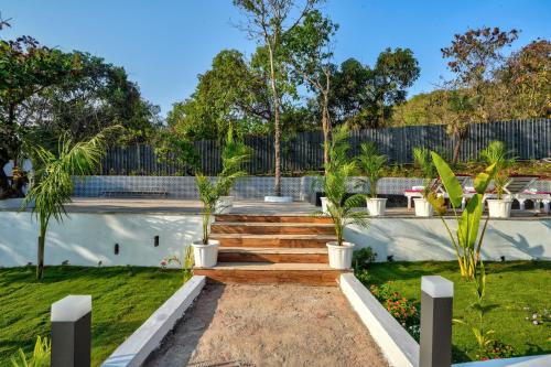a garden with a wooden staircase and palm trees at Amore Serenity Resort in Arambol