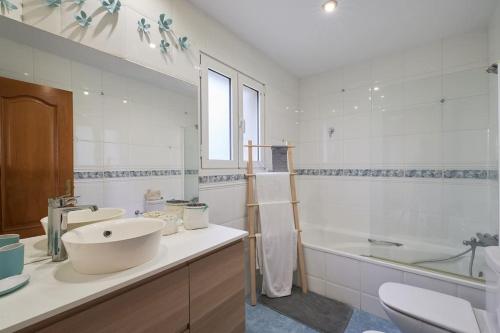 y baño blanco con lavabo, bañera y lavamanos. en SeaHomes Vacations - VILLA ROYER, en Tordera