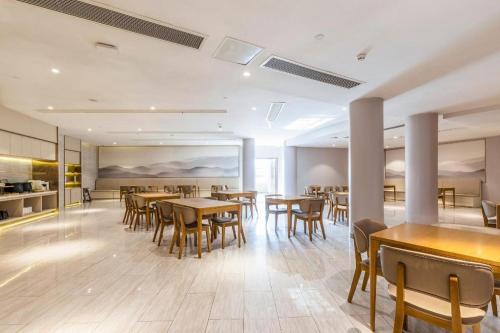 a dining room with tables and chairs in a building at Ji Hotel Wuhan Guanggu Software Park Minzu Avenue in Liufangling