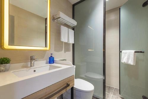 a bathroom with a sink and a toilet and a mirror at Hanting Premium Hotel Ji'nan Quancheng Road in Jinan