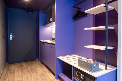 a kitchen with purple walls and a blue door at the niu Wave - Apartments in Karlsruhe