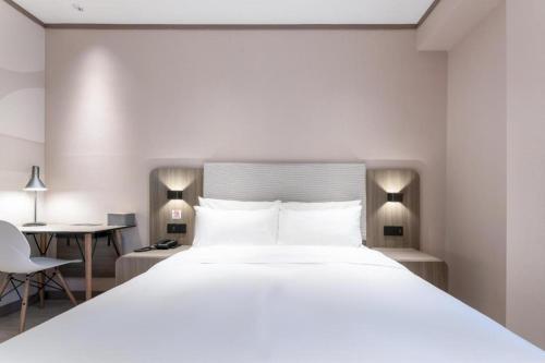 a bedroom with a large white bed and a desk at Hanting Hotel Ji'an Chengnan Administrative Center in Ji'an