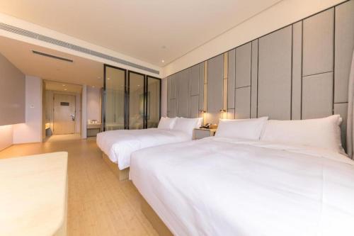 two beds in a hotel room with white sheets at Ji Hotel Ordos Wanzheng Plaza in Zhaoyoufang