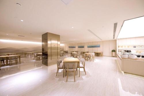 a dining room with tables and chairs and a kitchen at Ji Hotel Ordos Wanzheng Plaza in Zhaoyoufang