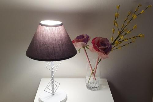 una lámpara y un jarrón con flores en una mesa en Sotto Le Stelle Home - una Baita in città, en Viterbo