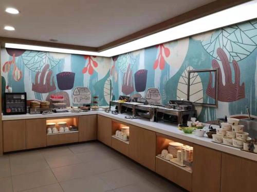 a restaurant with a buffet line with a colorful wall at Hanting Hotel Wuhan MinHang Xiaoqu in Wuhan