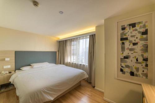 a bedroom with a large white bed and a window at Hanting Hotel Wuhan MinHang Xiaoqu in Wuhan