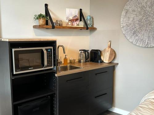 a small kitchen with a sink and a microwave at Hello Noordwijk - Studio Pietheinplein 1 in Noordwijk