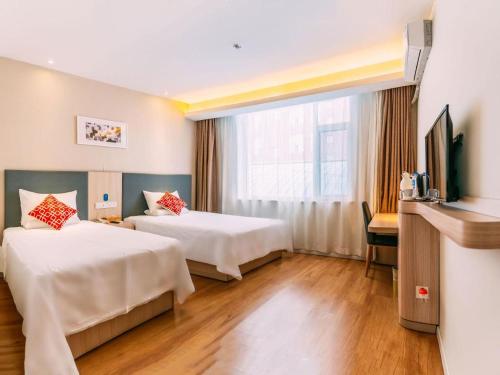 a hotel room with two beds and a television at Hanting Hotel Lvliang Citizen Square in Luliang