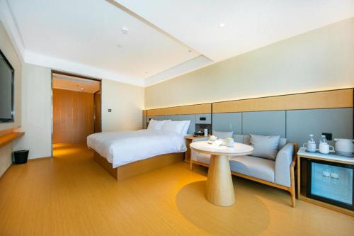 Xingqianjie的住宿－Ji Hotel Wenzhou Economic Development Zone Binhai Park，酒店客房配有床、桌子和沙发。
