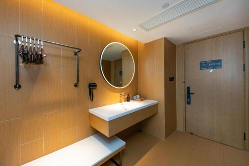 W łazience znajduje się umywalka i lustro. w obiekcie Ji Hotel Wenzhou Economic Development Zone Binhai Park w mieście Xingqianjie