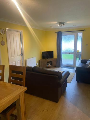 a living room with a black couch and a television at BumbleBee Lodge in Saint Cleer