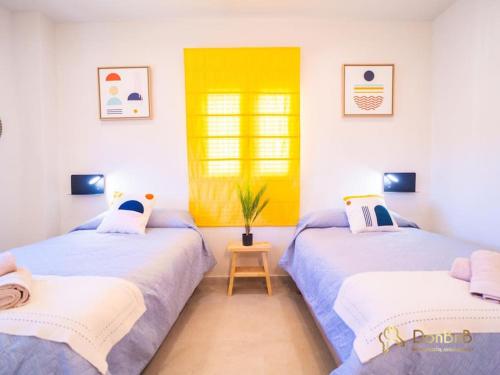 2 camas en una habitación con una pared amarilla en Cantos Apartment with Jacuzzi, en Ronda