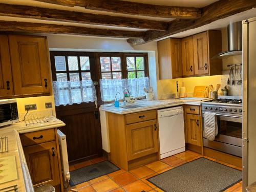 a kitchen with wooden cabinets and white appliances at Keepers Cottage in Wool
