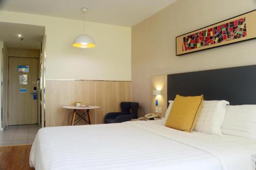 a hotel room with a large white bed and a chair at Hanting Hotel Linyi Mengshan Avenue in Linyi
