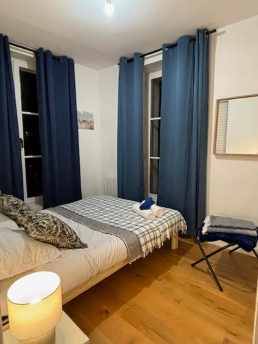 a bedroom with blue curtains and a bed and a chair at Relax 1 bedroom apartment - EG01 in Enghien-les-Bains
