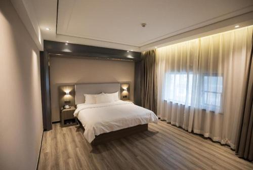 a bedroom with a large bed and a window at Hanting Premium Hotel Youjia Dengfeng Terminal in Dengfeng