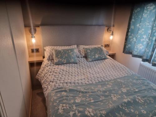 a bedroom with a large bed with blue sheets and pillows at Sunnyside lodge in Cirencester