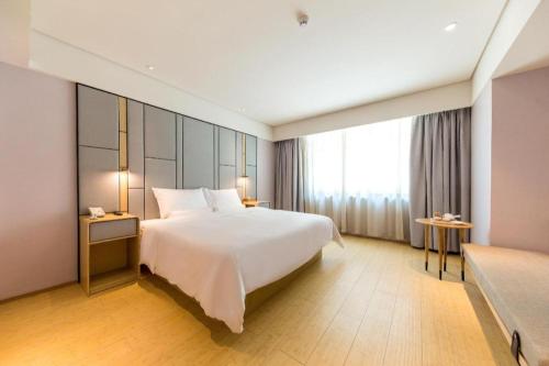a bedroom with a white bed and a large window at Ji Hotel Yantai Penglai Zhonglou Dong Road in Penglai