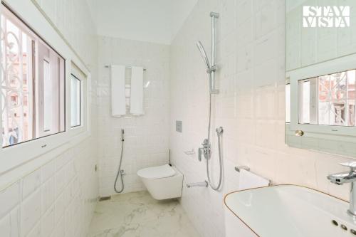 a white bathroom with a shower and a toilet at StayVista at The Ganga House - Holy River Varanasi in Varanasi