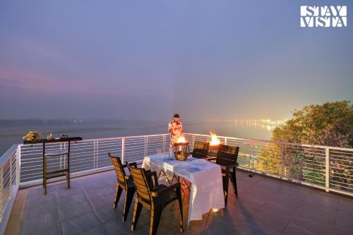 a person standing on top of a balcony with a table at StayVista at The Ganga House - Holy River Varanasi in Varanasi