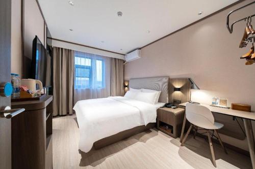 FeijiazhaiにあるHanting Hotel Shanghai Wujiaochang Shiguang Roadのベッドとデスクが備わるホテルルームです。