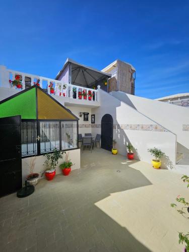 un edificio blanco con techo verde y algunas plantas en Dar Bargach, en Tánger