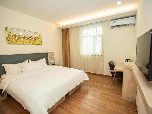 a bedroom with a large white bed and a television at Hanting Hotel Jiaozhou Jiaodong International Airport in Madian