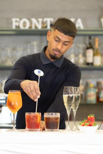 a man is preparing a drink at a table with glasses at Hotel Fontana Verona in Verona