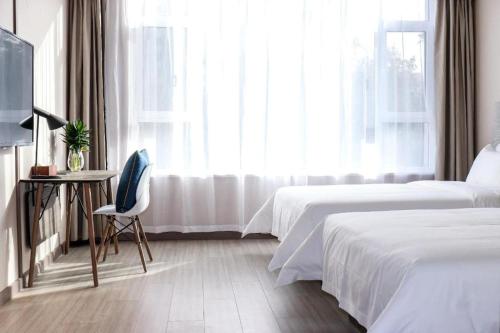 Cette chambre d'hôtel dispose de deux lits, d'une chaise et d'une fenêtre. dans l'établissement Hanting Hotel Yuncheng Xinjiangjiangzhou Avenue, à Xinjiang