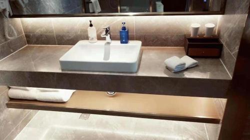 La salle de bains est pourvue d'un lavabo et de serviettes sur un comptoir. dans l'établissement Hanting Hotel Yuncheng Xinjiangjiangzhou Avenue, à Xinjiang
