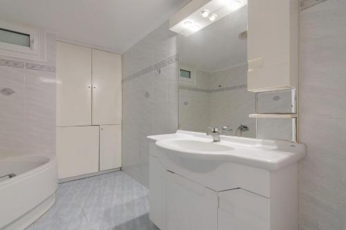 La salle de bains blanche est pourvue d'un lavabo et d'une baignoire. dans l'établissement Comfy apartment for 6 people in Heraklion, à Héraklion