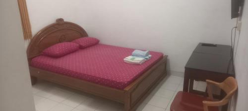 een klein bed met roze lakens en kussens in een kamer bij Hotel Purnama 5 in Ngaglik