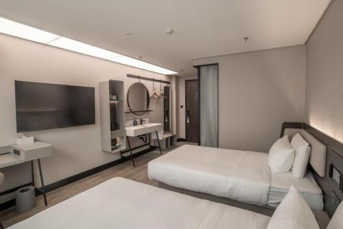 Een bed of bedden in een kamer bij Hanting Hotel Qinhuangdao Hebei Street Yanshan University