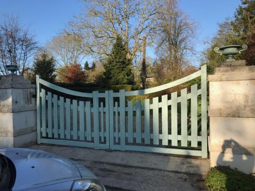a white fence with a gate in a driveway at Le Logis Fleurs et jardins de Pitry in Thierville