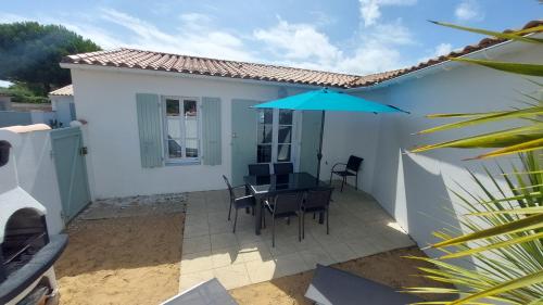 um pátio com uma mesa e um guarda-chuva em Maison "PIVOINE" proche de la plage em Le Bois-Plage-en-Ré