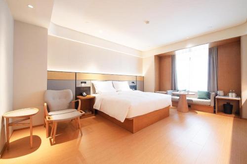 ein Hotelzimmer mit einem Bett und einem Stuhl in der Unterkunft Ji Hotel Harbin West Railway Station in Harbin